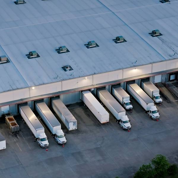 An overview shot of semi trucks and trailers parked at a warehouse.