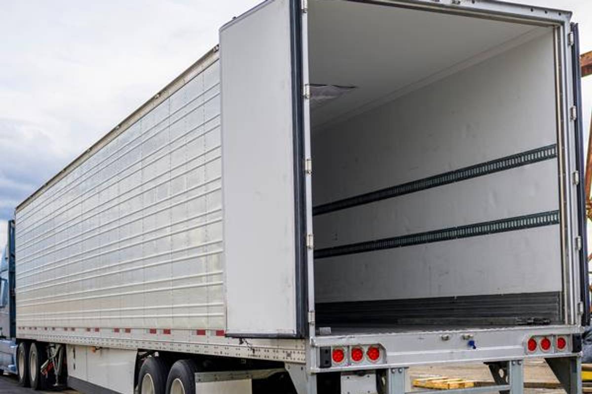 Back of a white semi-truck showing an empty trailer.