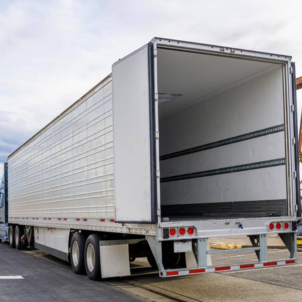Back of a white semi-truck showing an empty trailer.