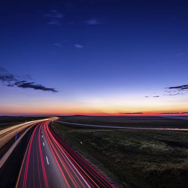 Brake lights shine brightly on a road at night.
