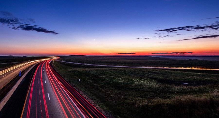 Brake lights shine brightly on a road at night.