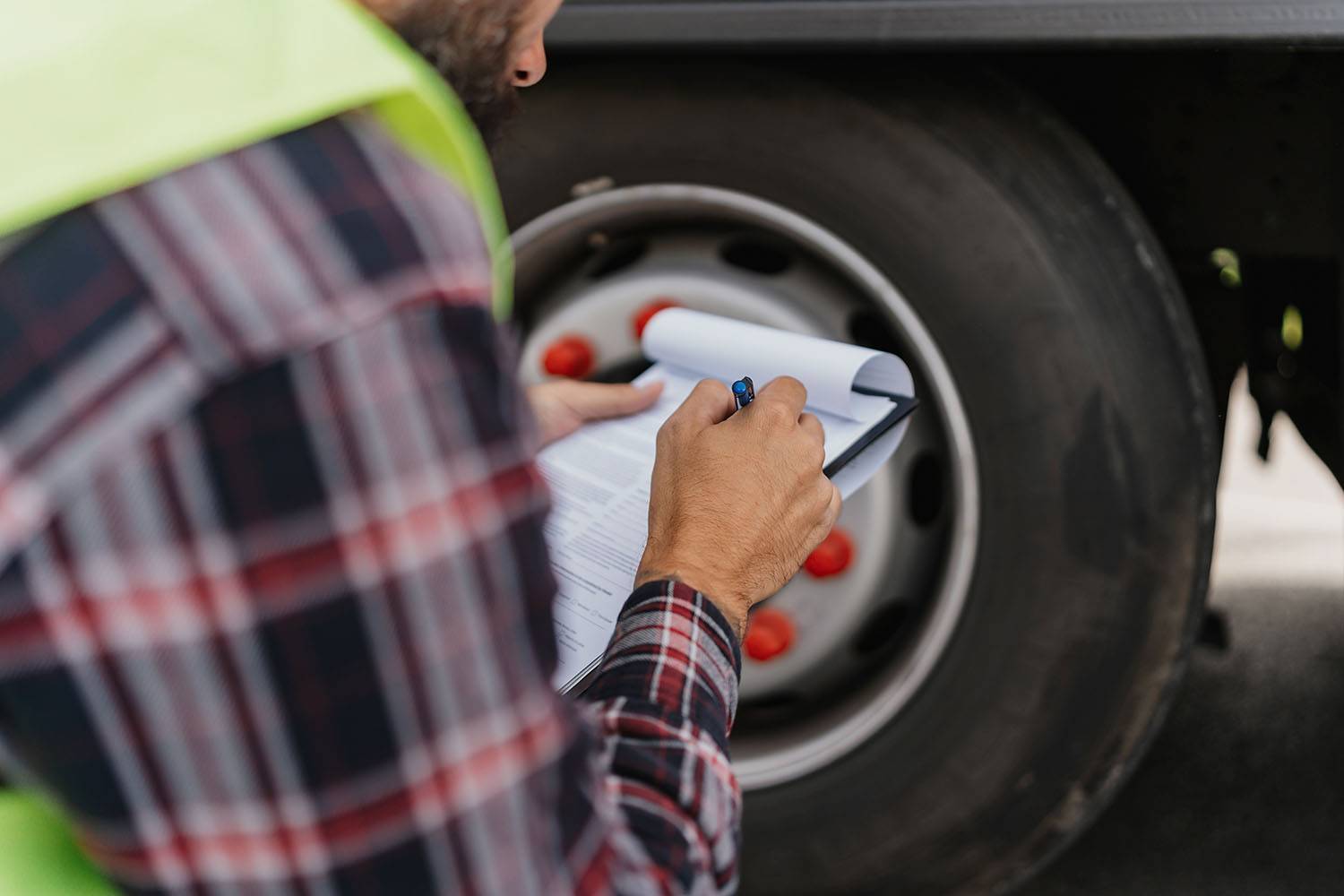 Close-up of a man holding a pen and paper checklist, making marks on the checklist.