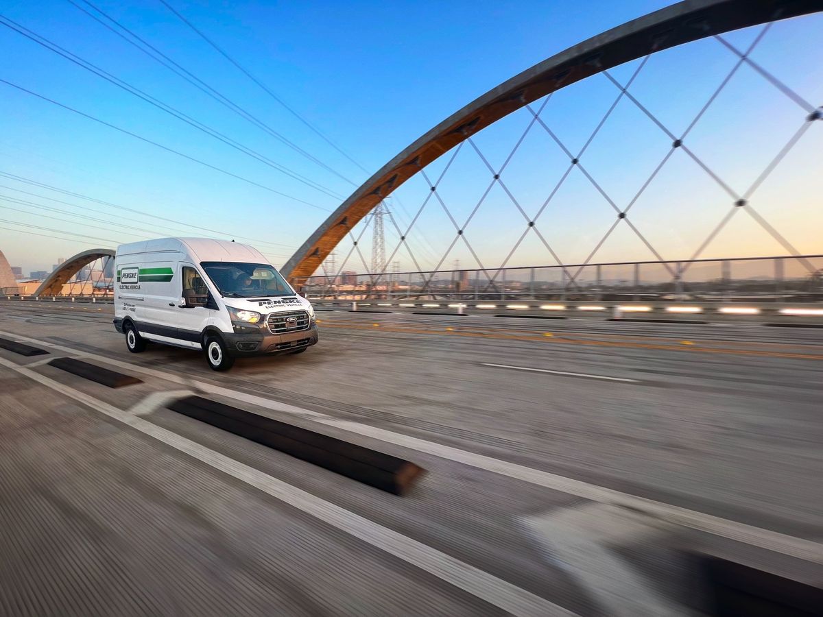 Electric transit van driving across a bridge.