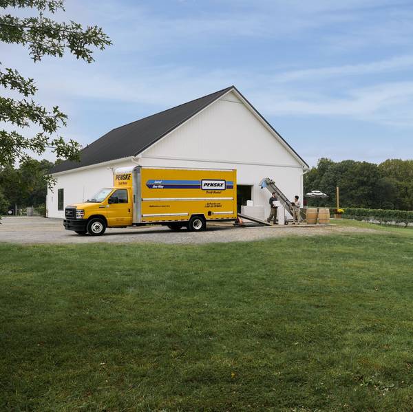Employees at a winery load the back of a yellow Penske Truck.