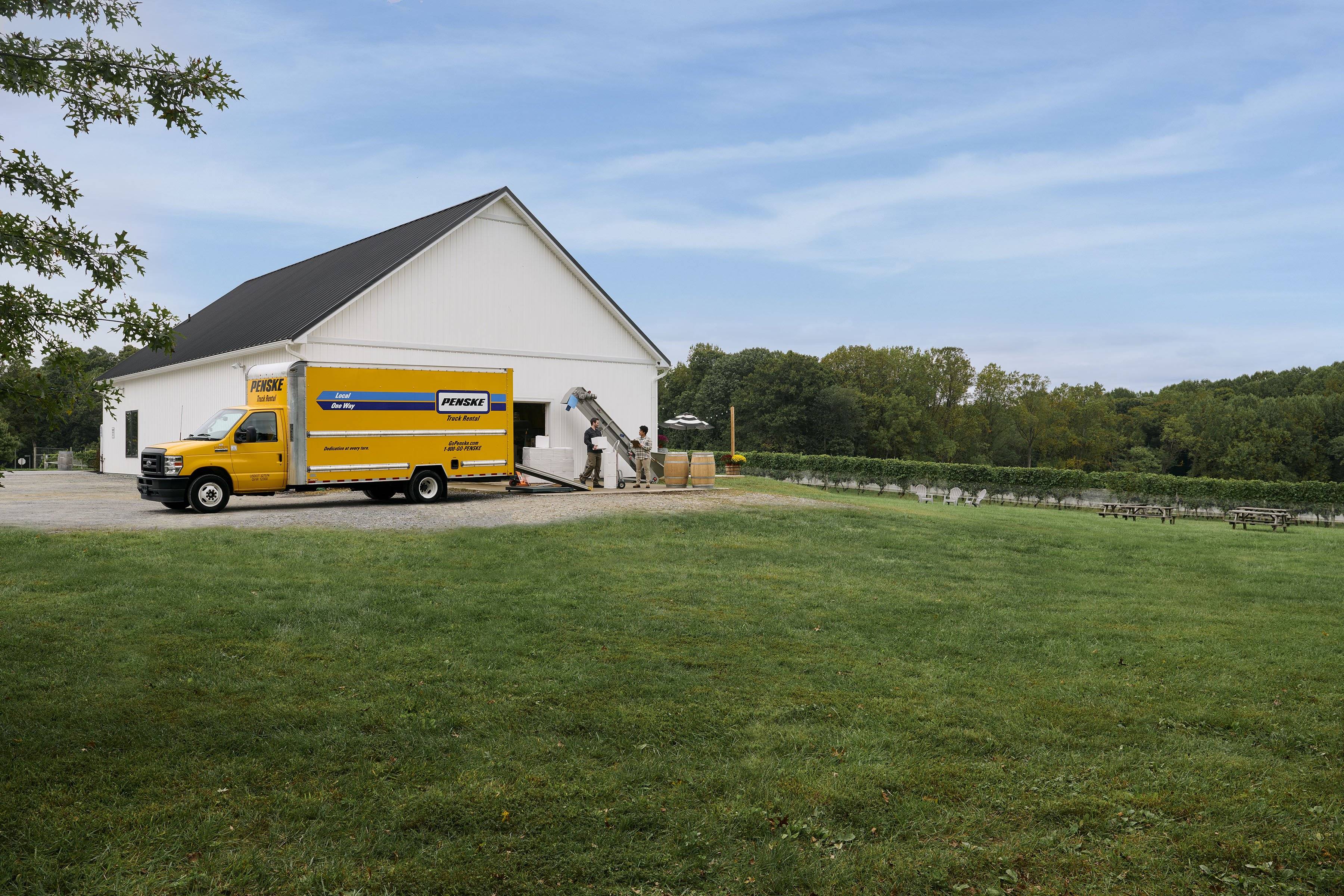 Employees at a winery load the back of a yellow Penske Truck.