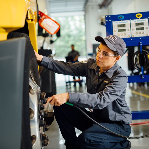 Fleet Maintenance technician puts air into a truck tire.