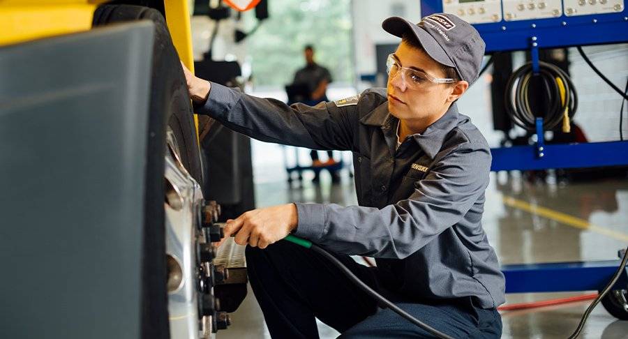 Fleet Maintenance technician puts air into a truck tire.