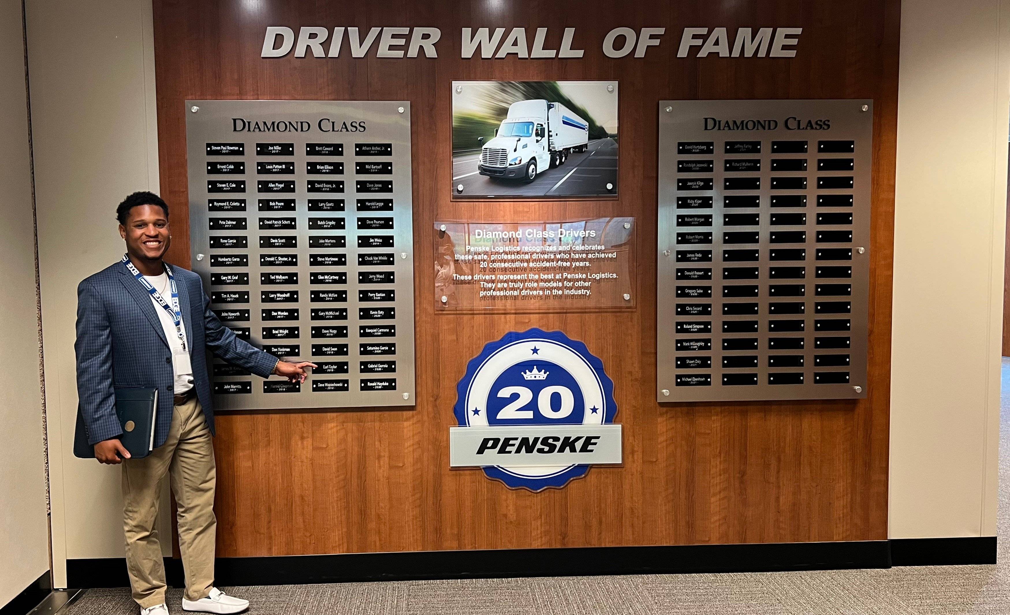 Man pointing to his name on a "Driver Wall of Fame."