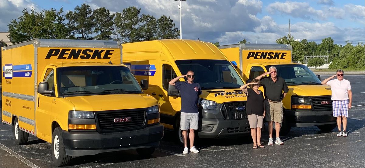 military family saluting in front of penske trucks