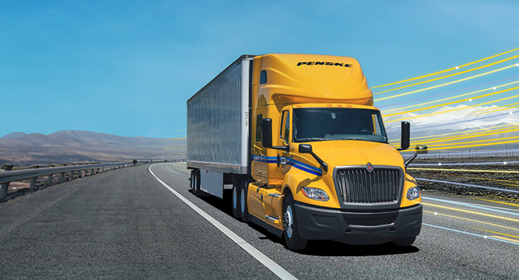Penske truck driving down a highway in the desert hills.