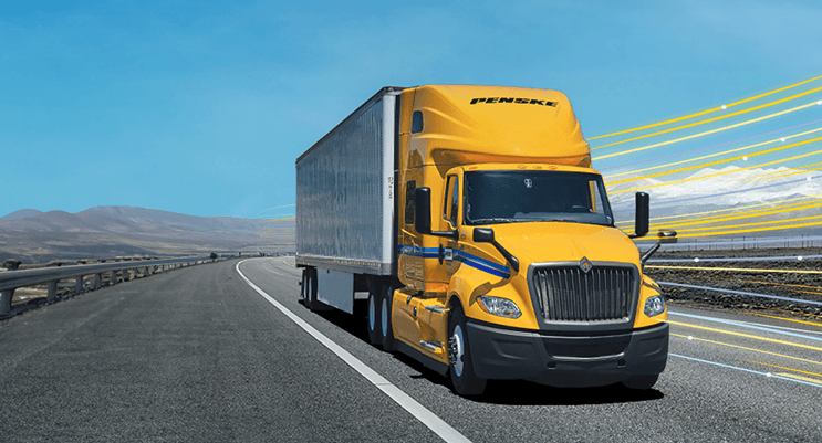 Penske truck driving down a highway in the desert hills.