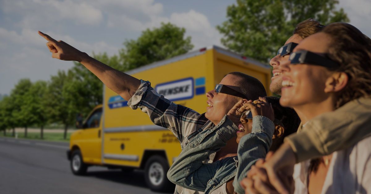 People wearing eclipse glasses and pointing toward the eclipse.