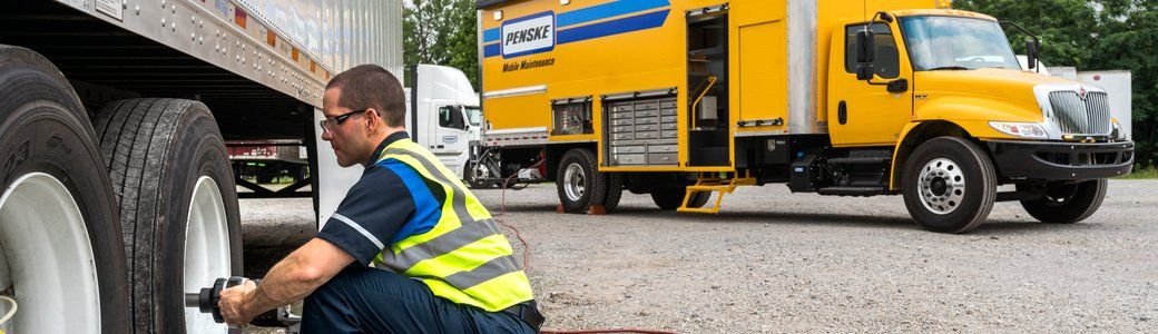 Technician servicing truck with Penske Mobile Maintenance truck in the background