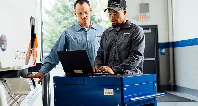 Technicians by truck performing diagnostics with laptop