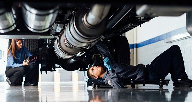Technicians servicing the underside of a truck