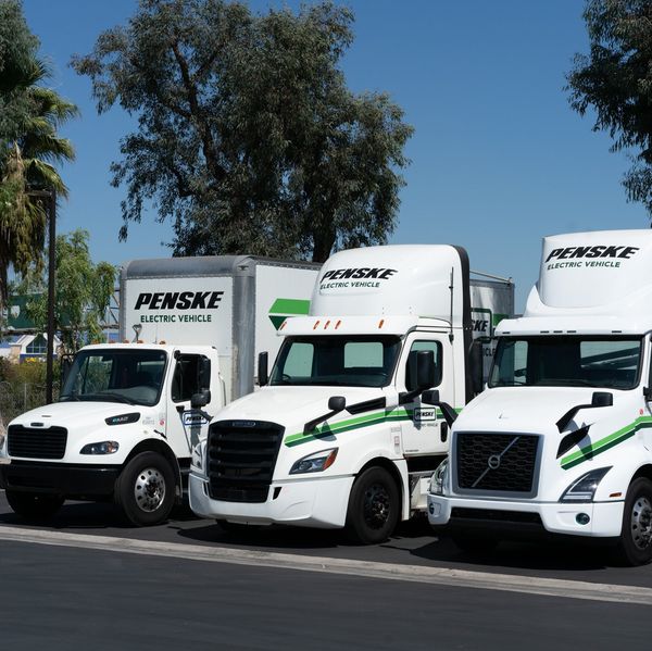 Three electric Penske vehicles parked in a row.