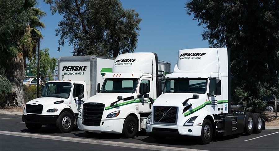 Three electric Penske vehicles parked in a row.