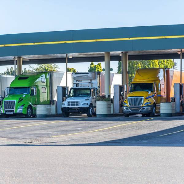 Three trucks lined up at a fueling station.