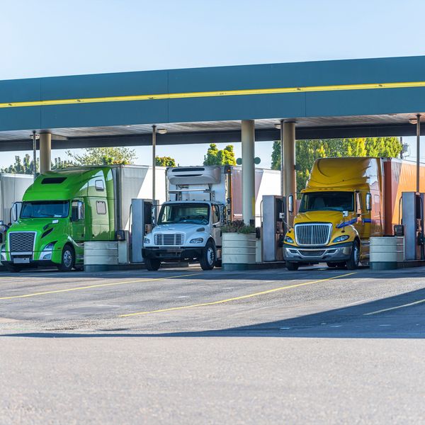 Three trucks lined up at a fueling station. 