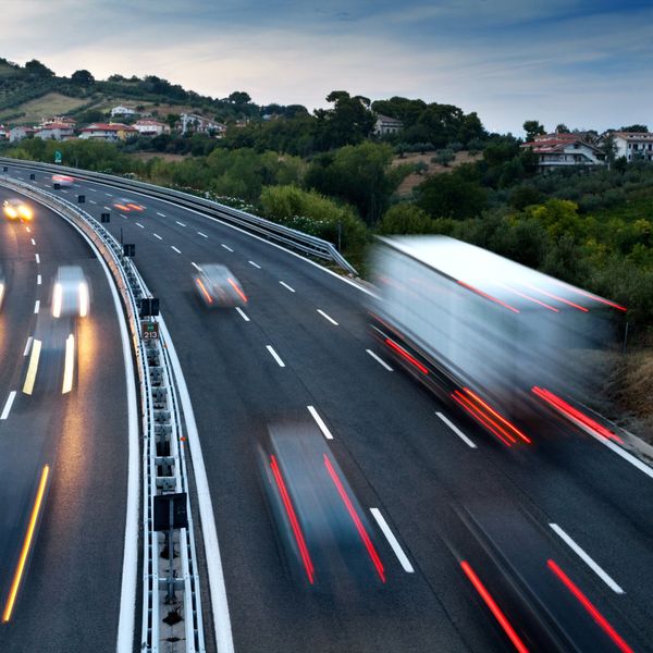 Trucks and cars hit their brakes as they drive up and down a freeway.