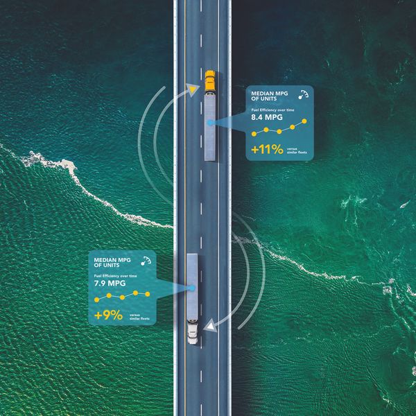 Two Penske trucks driving over a bridge with graphics attached to them showing MPG data.