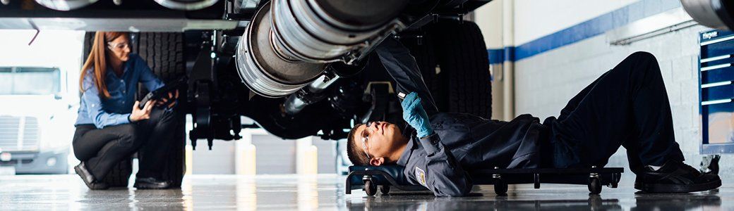  Two technicians servicing the underside of a truck
