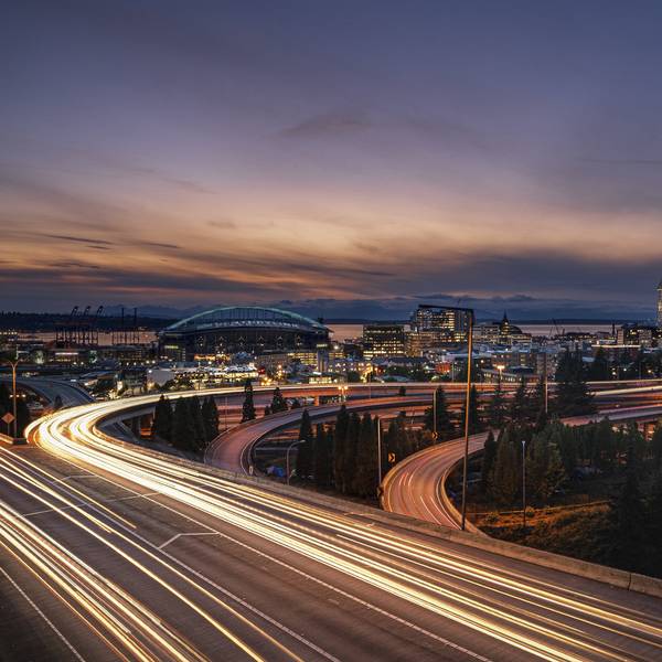 Vehicles speeding down a freeway outside a city at night.