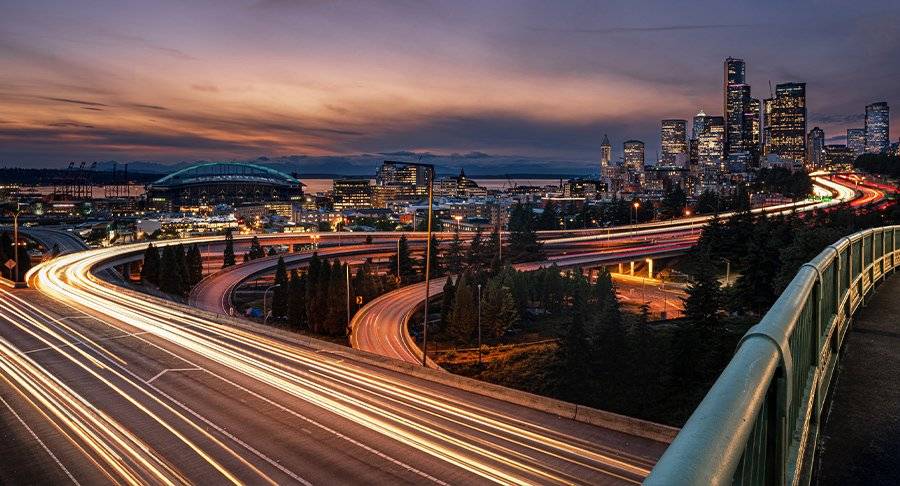 Vehicles speeding down a freeway outside a city at night.