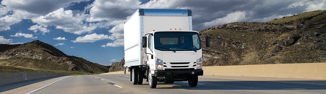 White light-duty truck driving down the highway