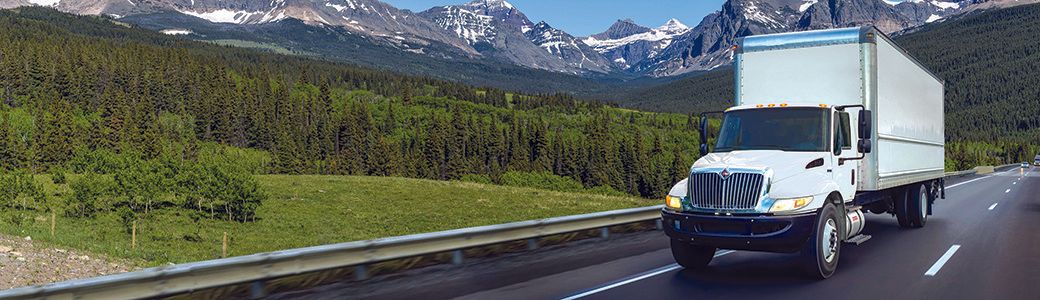 White medium-duty truck driving down the highway