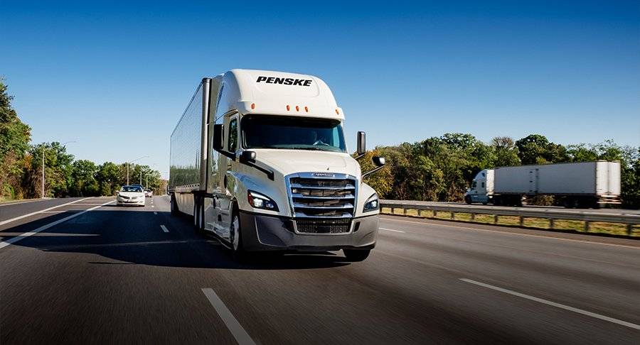 White Penske Semi truck drives on a freeway.