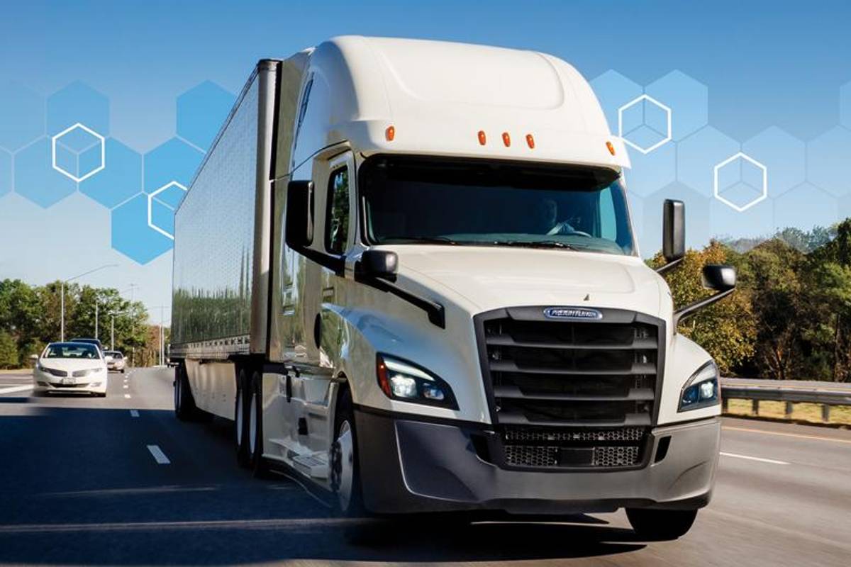 White Penske semi-truck drives over a bridge.