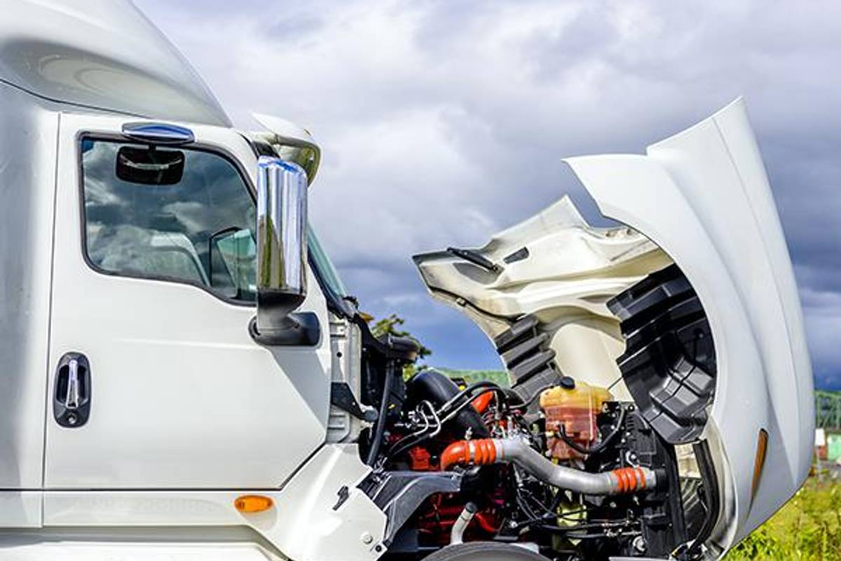 White semi-truck with front hood open for repairs