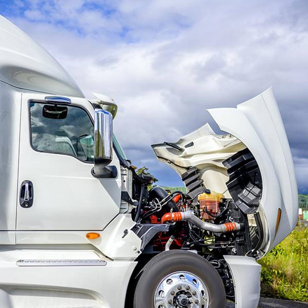 White semi-truck with front hood open for repairs