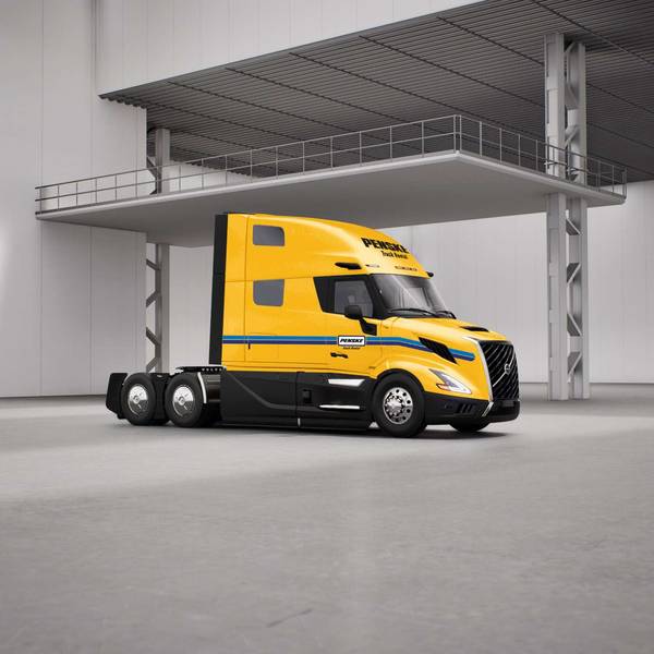 Yellow Penske semi-truck with no trailer sitting in a warehouse.